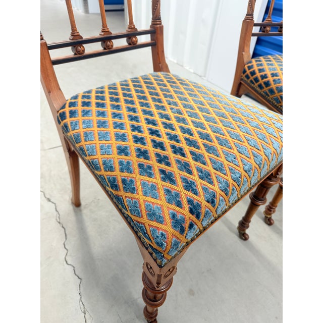 A richly detailed pair of English Gothic Revival walnut side chairs, dating to around 1870, distinguished by their...