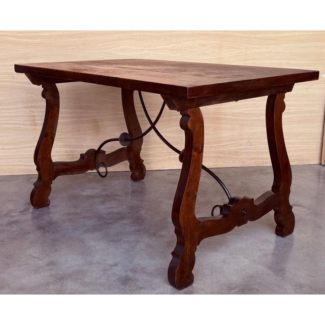 Dining table made of walnut with carved lyre legs and heavy top. The lyre legs are very thick. Beautiful iron stretcher,...
