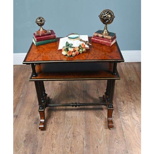 A refined Victorian two-tier dumb waiter table / book shelf in richly figured amboyna with elegant ebonised detailing The...