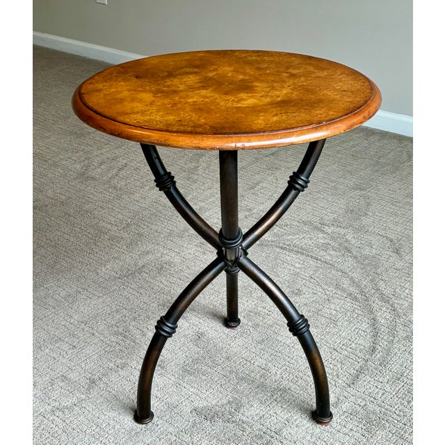 An elegant round accent table from the Milling Road collection by Baker Furniture, featuring a richly figured burl wood...
