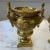 Heavily ornamented gilt metal urns detailed with Grecian imagery, lions’ heads. Each urn measures 8.25” to top of figure;...