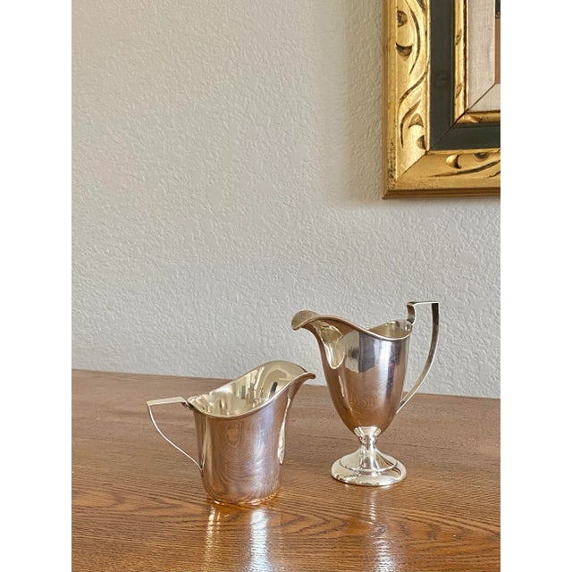 A set of two coordinating sterling silver creamers in a Neoclassical style. Wonderful forms that would be perfect for...