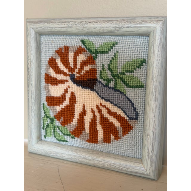 Charming vintage needlepoint featuring a beautifully stitched nautilus shell in warm shades of rust, cream, taupe, and...