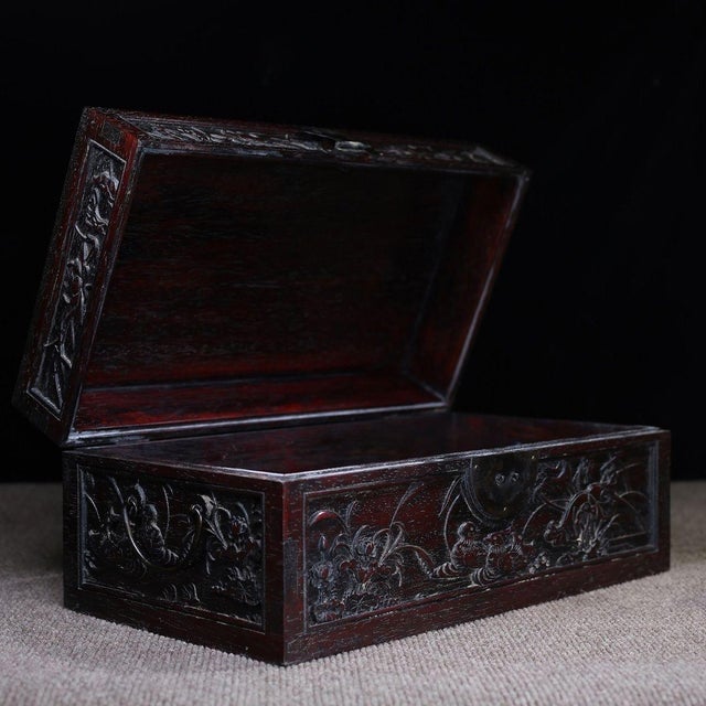 A beautifully crafted Chinese hardwood box, likely made of Zitan wood, featuring deep relief carvings. The lid is...