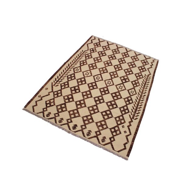 Add a touch of elegance to your home with this casual chic handwoven tribal kilim wool rug. Constructed on a loom by nomad...