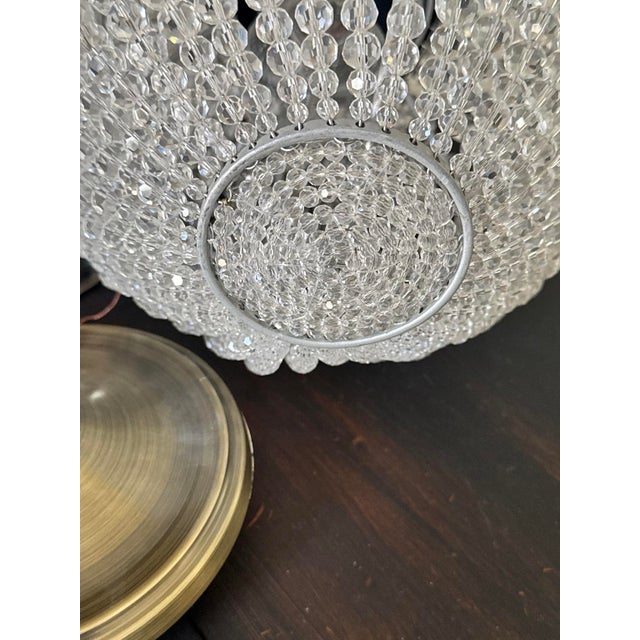 Faceted crystal-style beads form a glowing globe, paired with antique brass and a mid-century inspired silhouette for a...