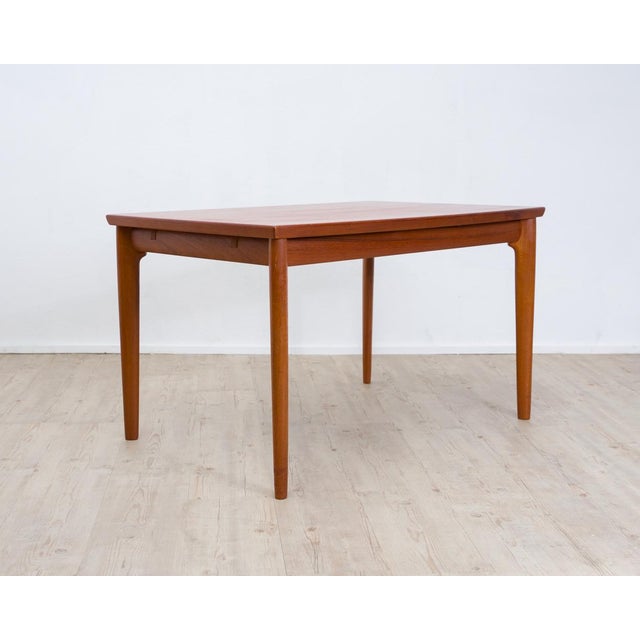 Large teak dining table with an elegant, slightly elliptical shape and two extension leaves. A masterpiece by Danish...