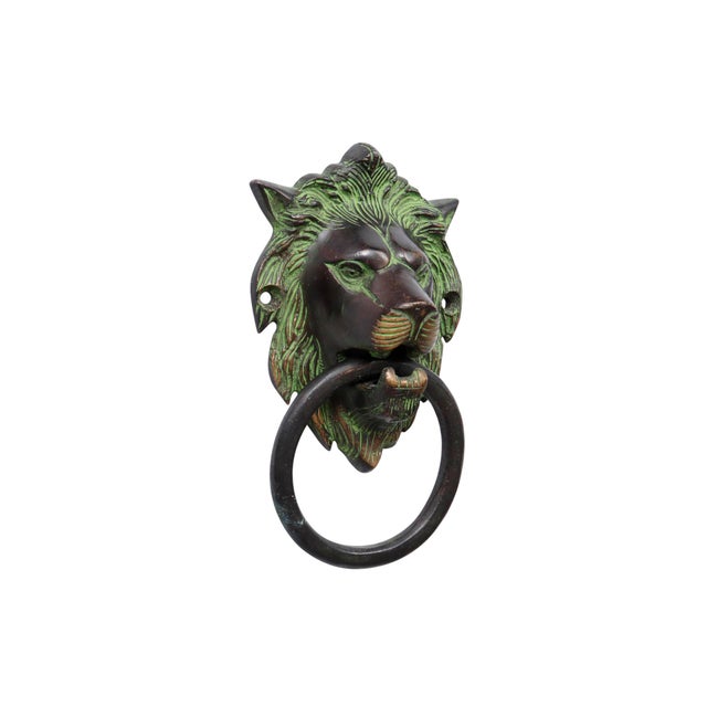 A solid green brass lion's head door knocker with intricately cast details throughout. We have more door knockers...