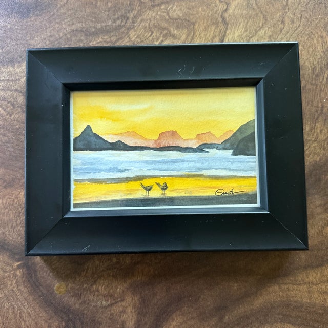 Set against the serene backdrop of a golden sunset, “Golden Hour Stroll” features two small shorebirds exploring a quiet...