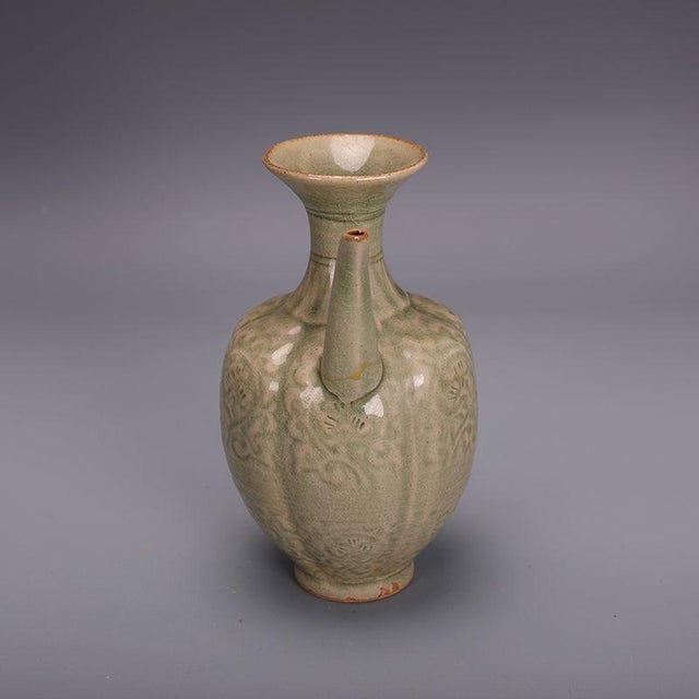 This elegant ceramic ewer is a beautiful decorative piece inspired by traditional Chinese pottery. The vessel features a...