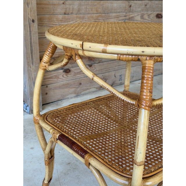 A classic Old Florida coastal rattan side table featuring a woven cane top and convenient lower shelf. The sculptural...