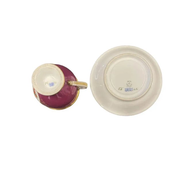 Royal Copenhagen Empire-style cup and saucer feature hand-painted floral motifs and gilded accents. The cup stands at a...