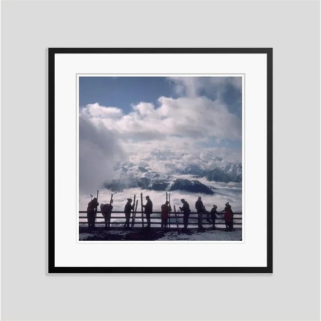 Verbier View' by Slim Aarons Open Edition Skiers admire the view across a valley of clouds at Verbier, 1964. An exquisite...