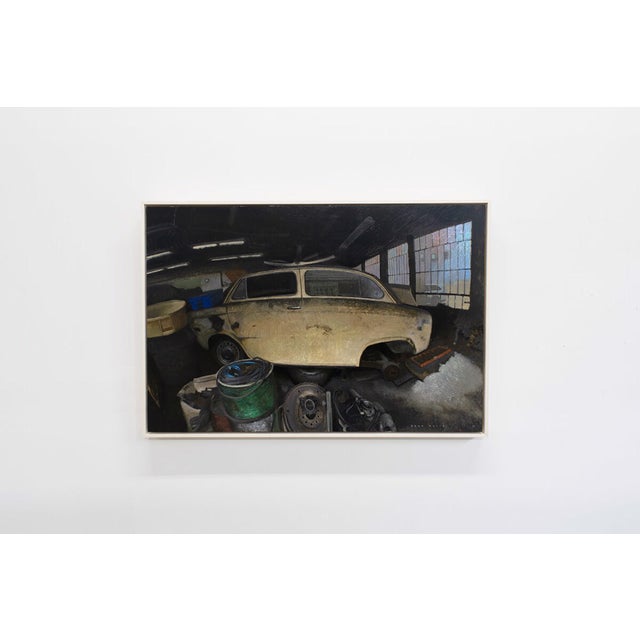 This oil on wood panel artwork captures a vintage car nestled within a cluttered garage, surrounded by tools and machinery...
