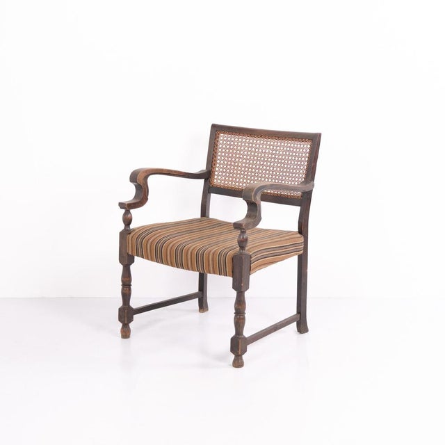 Antique armchair from the 1920s, made of oak. The chair features original upholstery in light-coloured fabric together...
