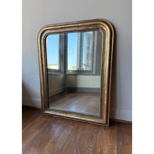 A 19th Century French Louis Philippe mirror with a gilded wooden frame, featuring the period’s characteristic rounded...