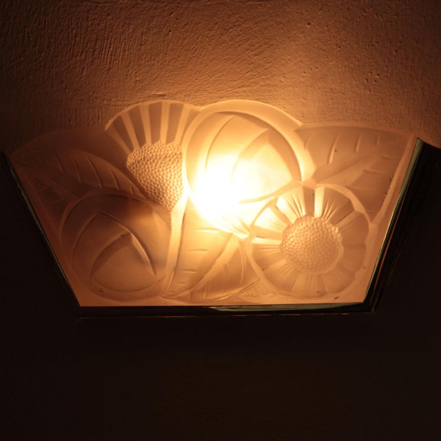 A set of two Degue Art Deco wall lights with geometric floral motifs in the glass. The metal is re-nickeled brass....