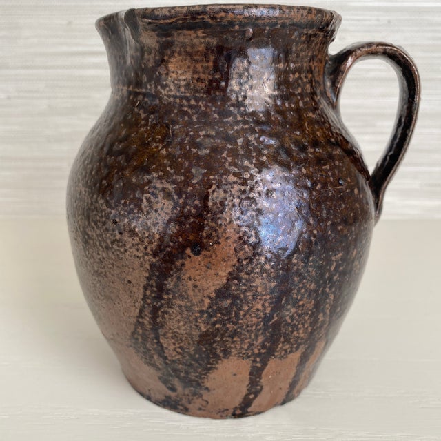 One of a kind traditional southern style pottery pitcher in a mottled brown drippy glaze finish. Nice lustre remains on...