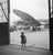 Young Traveller by Toni Frissell A young girl stands in her raincoat awaiting a plane to be refilled for her travels....