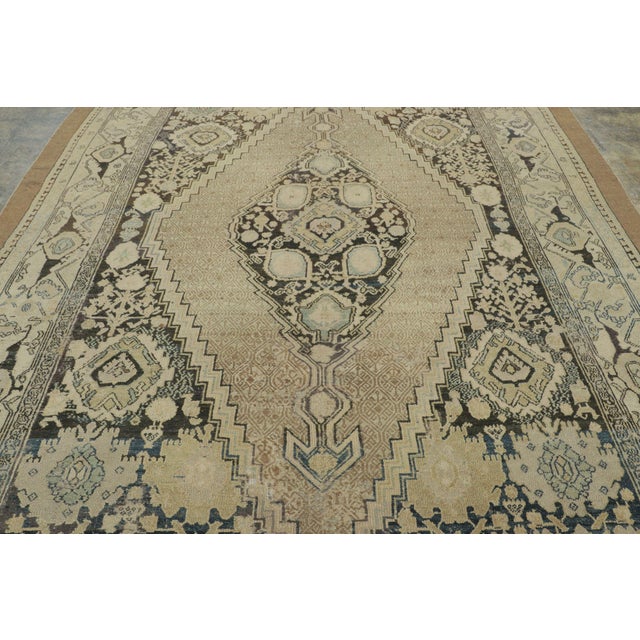 Hand-knotted in wool, this 9x13 antique rug, circa 1900-1920, is a quintessential example of Persian craftsmanship from...