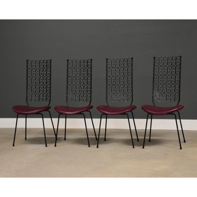 A set of four mid century modern wrought iron dining chairs by Arthur Umanoff for Shaver-Howard. New maroon red vinyl....