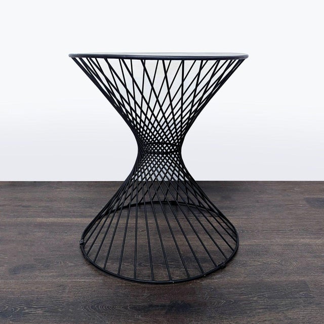 Upgrade your space with this modern accent table, featuring a unique hourglass wire frame design and a smooth, round top....