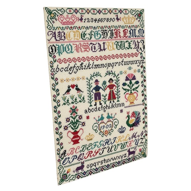 Vintage hand-stitched cross stitch alphabet sampler featuring multiple alphabet styles in upper and lowercase, numbers...
