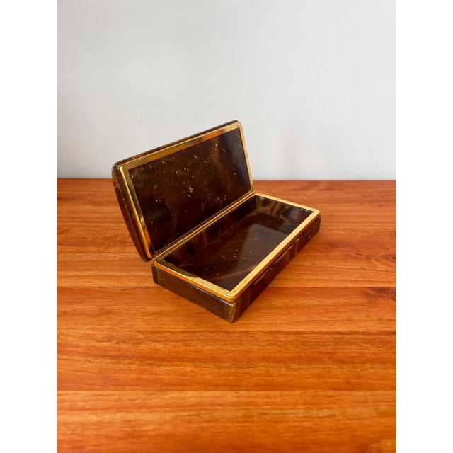 An alabaster jewelry box, in a pleasant shade of brown from the 1960’s. The lid is secured to the base with a gold-colored...