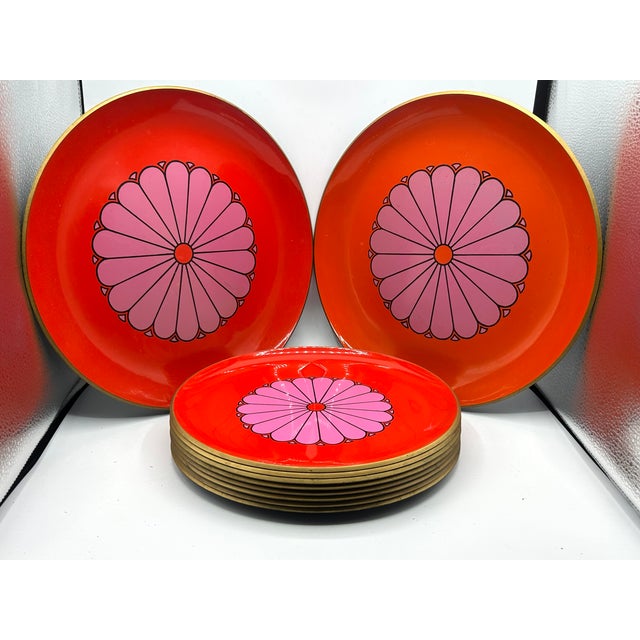 A ten-piece Japanese melamine set with vivid orange-red surfaces, oversized pink flowers outlined in black, and gold-toned...