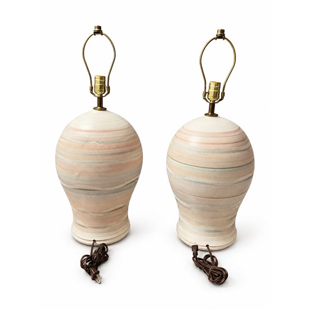 A striking matching pair of vintage ceramic table lamps featuring substantial, sculptural urn-shaped bodies and softly...