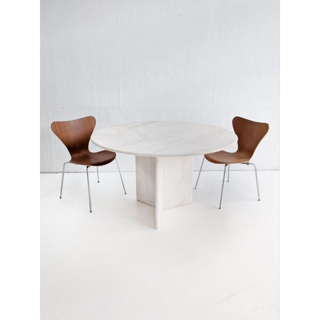 Round postmodern dining table, made out of Italian travertin. The table features a circular tabletop on an architectural...