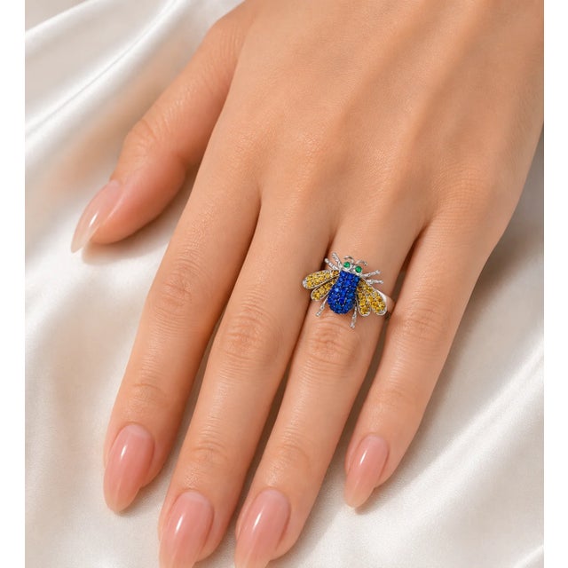 This 18K white gold ring features hand-cut natural sapphires, brilliant round champagne diamonds, and 2 round natural...