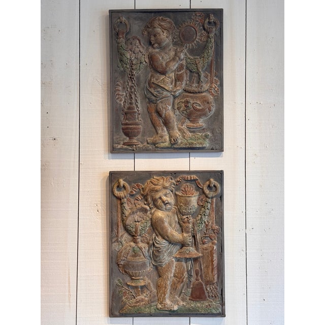 Pair of 19th century carved wood relief panels depicting winged cherubic figures in high relief with classical motifs...