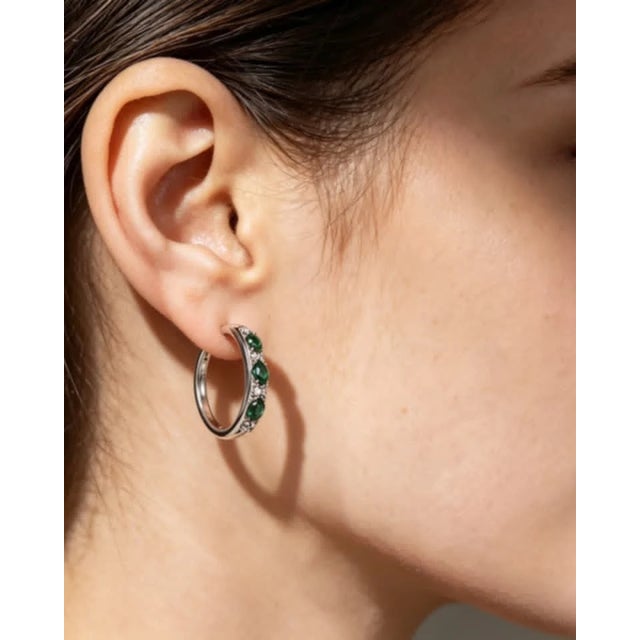 Elegant 14K white gold hoop earrings featuring 6 natural oval emeralds and 16 brilliant round diamonds totaling 0.2...
