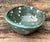 This vintage green glazed studio pottery bowl is a compelling example of mid-century ceramic artistry, celebrating the...