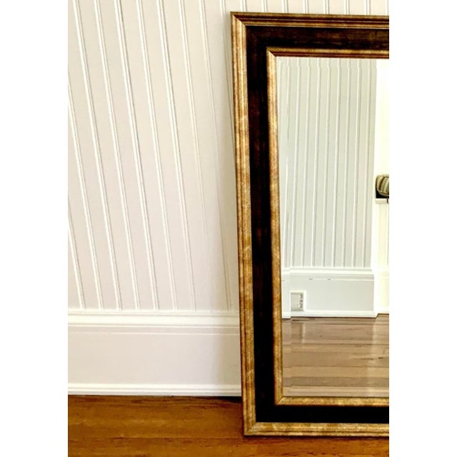 A vintage large framed rectangular wall mirror with beveled glass and a two-tone finish: a distressed dark bronze/black...