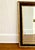 A vintage large framed rectangular wall mirror with beveled glass and a two-tone finish: a distressed dark bronze/black...