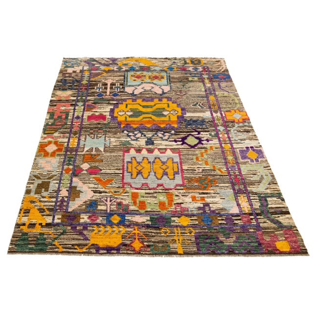 This contemporary Moroccan-style wool rug features a captivating brown backdrop with multicolor flowers crafted in an all-...