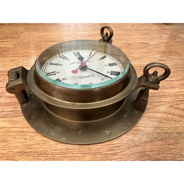 Classic maritime-style wall clock featuring a solid brass porthole case with hinged bezel and working latch. The clock has...