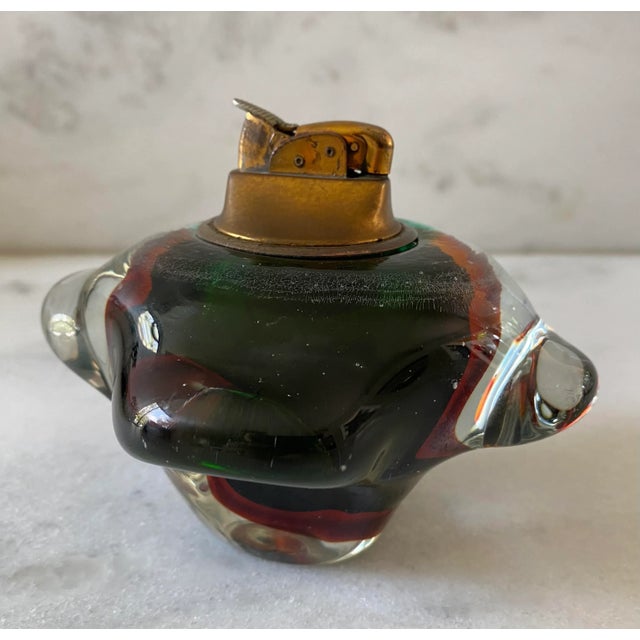 Vintage 1970s Murano Glass paperweight lighter in a beautiful green amber color and unique shape. Lighter is not currently...
