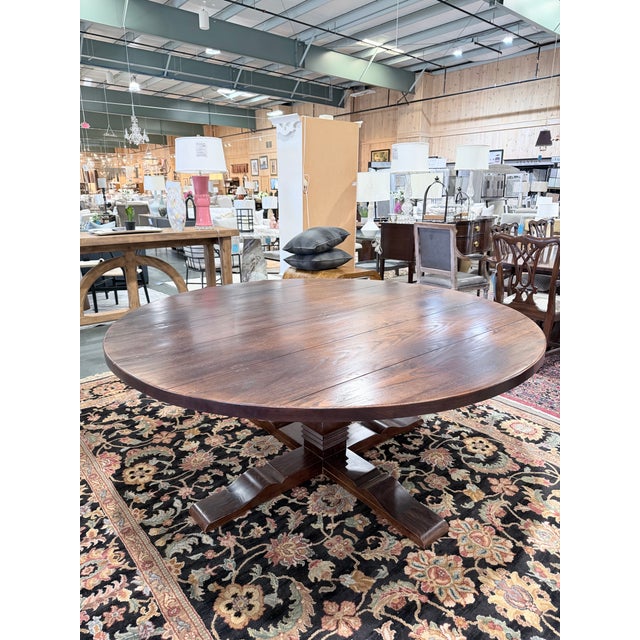 A substantial custom made round farmhouse dining table crafted in chestnut, featuring a wide plank top with rich natural...