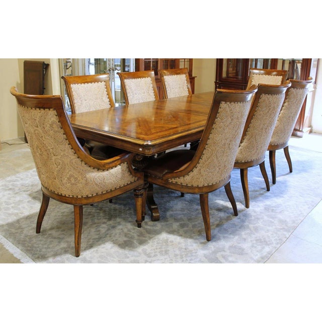 This formal dining set features a richly detailed rectangular table with carved edges and sturdy, sculpted legs. The eight...