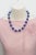 This bold and vibrant necklace features a strand of richly colored round amethyst beads, each displaying deep violet...