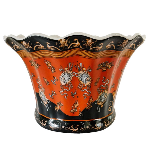 A striking ceramic cachepot featuring a bold terracotta and black color palette and intricate neoclassical motifs,...