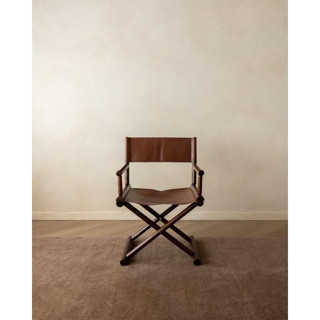 A vintage italian modern folding director’s chair in dark stained wood and warm brown leather, produced in italy during...