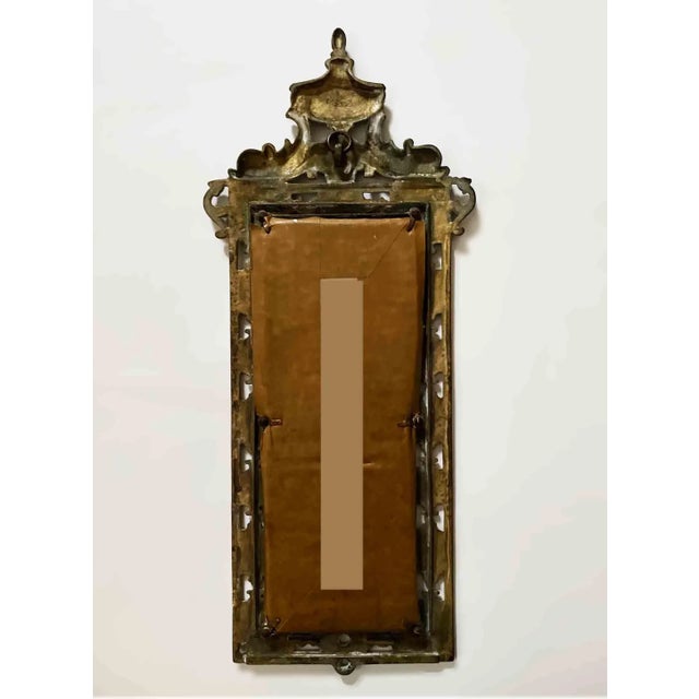 Vintage vertical brass mirror. Intricate classic design with crest in the form of dolphins flanking urn.