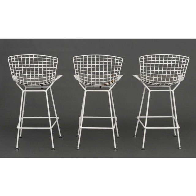 Set of Three Harry Bertoia White Patinated Wire Bar Stools, with gray leather cushions. 39" H x 21" W x 19" D; seat: 28.5"...