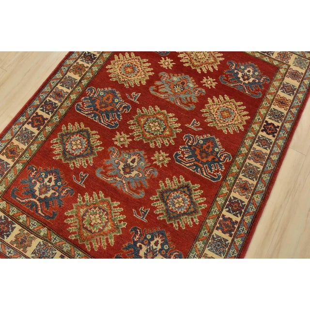 A tribal Caucasian Kazak rug hand-knotted with fine wool on a cotton foundation. This rug features geometric motifs set...