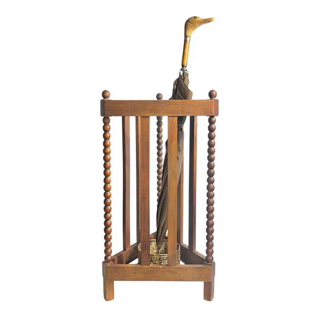 Charming antique umbrella and walking stick stand crafted in solid oak, featuring classic bobbin-turned columns and a...