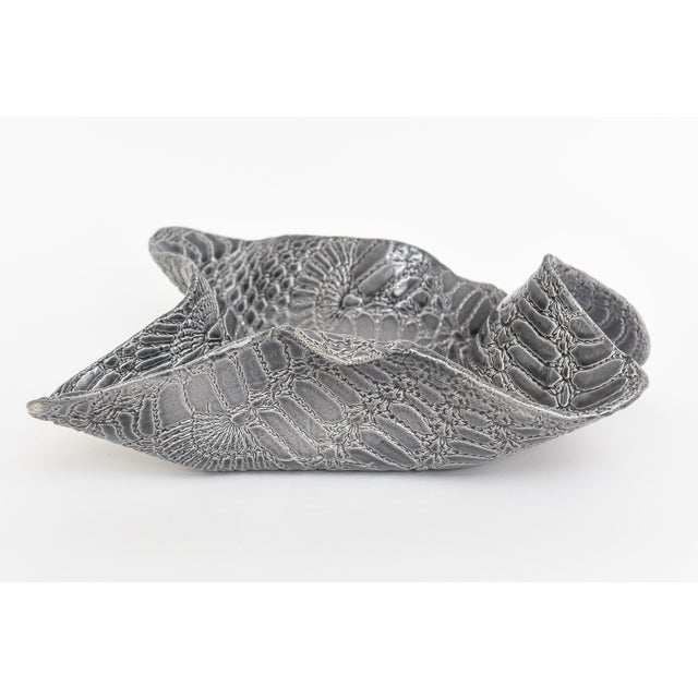 This most unusual biomorphic ceramic bowl has the embossed design of snakeskin. The gradients of colors of gray, to...
